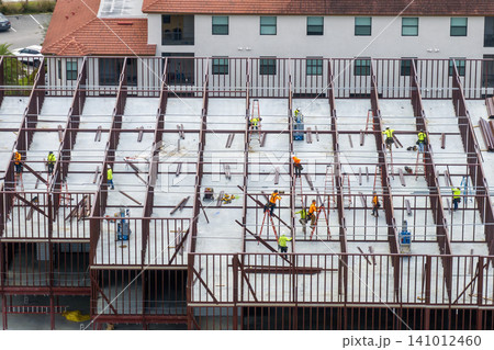 Workers assembling metal frame building at industrial construction site. Housing development in America. Real estate market in the USA Workers assembling metal frame building at industrial construction site. Housing development in America. Real estate market in the USA 141012460