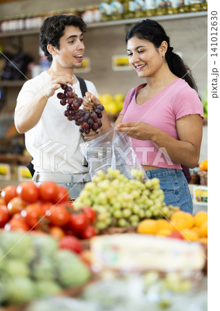 Couple choosing grapes at grocery store Couple choosing grapes at grocery store 141012630