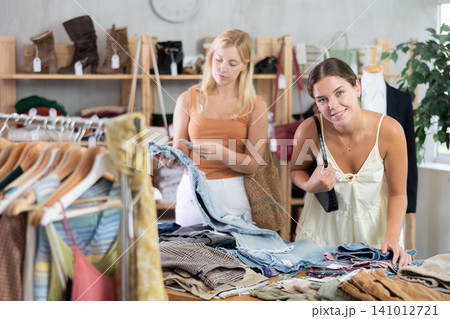 Fashionista girls near showcase examine goods, buying shorts or trousers 141012721