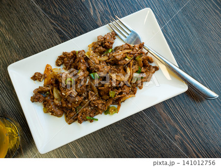 Portion of Chinese food is pieces of fried beef tenderloin with soy-cumin sauce 141012756