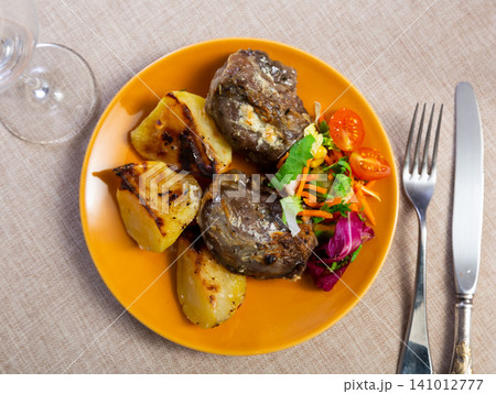 Pork cheek served with potatoes and vegetable salad Pork cheek served with potatoes and vegetable salad 141012777