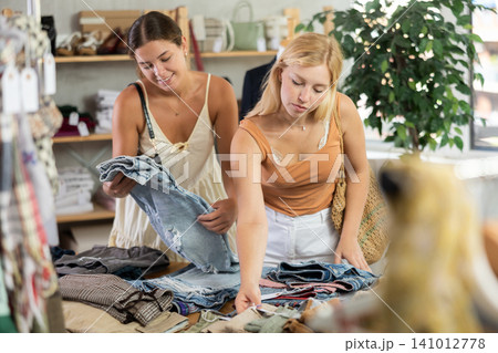 Two women choosing high-quality jeans in the store Two women choosing high-quality jeans in the store 141012778