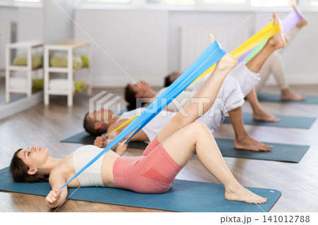 Young girl practicing leg stretching with band lying back Young girl practicing leg stretching with band lying back 141012788