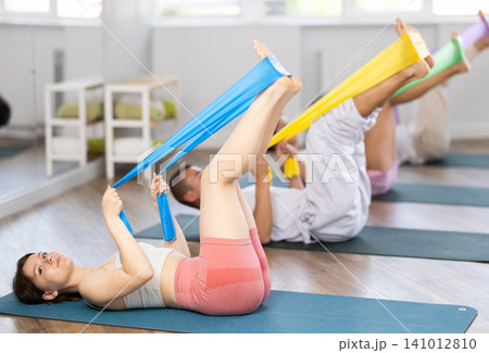Young girl practicing leg lift with band on knees lying on the side Young girl practicing leg lift with band on knees lying on the side 141012810