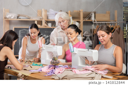 Group of women sew and draw pattern at sewing workshop Group of women sew and draw pattern at sewing workshop 141012844
