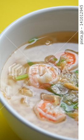 rice soup with shrimp in white bowl on yellow background rice soup with shrimp in white bowl on yellow background 141012945