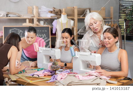 Group of women sew and draw pattern at sewing workshop Group of women sew and draw pattern at sewing workshop 141013187
