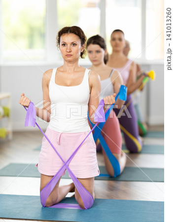 Women are doing stretching exercise with resistance bands in gym. Teamwork, good mood and healthy lifestyle concept Women are doing stretching exercise with resistance bands in gym. Teamwork, good mood and healthy lifestyle concept 141013260