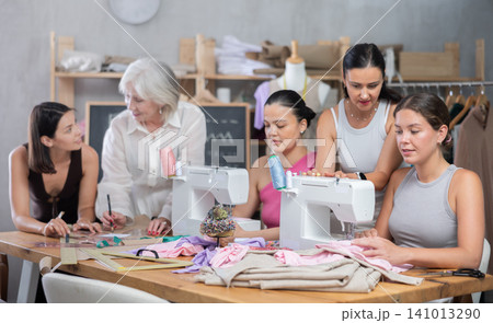 Group of busy women sewing and drawing with teacher at dressmaking courses 141013290
