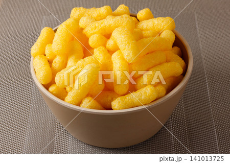 Corn sticks in a clear bowl on a neutral, textured background Corn sticks in a clear bowl on a neutral, textured background 141013725