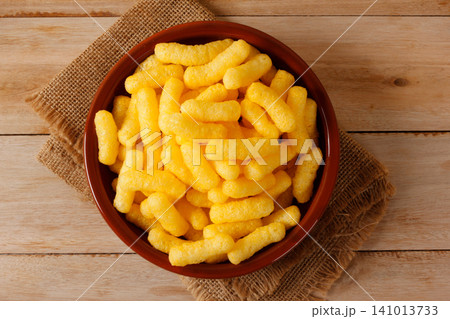 Corn sticks in a brown bowl on a jute cloth and a wooden surface. Corn sticks in a brown bowl on a jute cloth and a wooden surface. 141013733