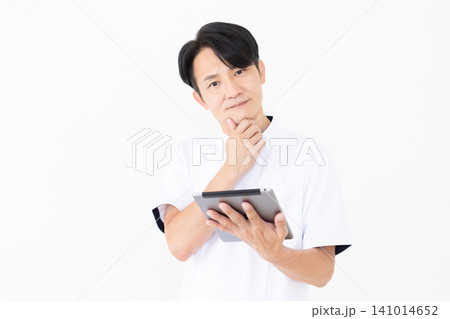 タブレットを持って悩む白衣を着たミドル男性の鍼灸師・整体師 141014652