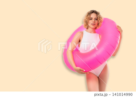 Woman showcases trendy swimsuit while holding bright float. Summer vibes and beauty concept Woman showcases trendy swimsuit while holding bright float. Summer vibes and beauty concept 141014990