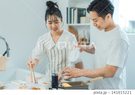 大きな笑顔でお弁当の準備を楽しむカップルの明るいキッチンシーン 大きな笑顔でお弁当の準備を楽しむカップルの明るいキッチンシーン 141015221