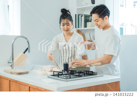 明るく話しながらお弁当の準備を進める仲良しカップルのキッチンシーン 明るく話しながらお弁当の準備を進める仲良しカップルのキッチンシーン 141015222