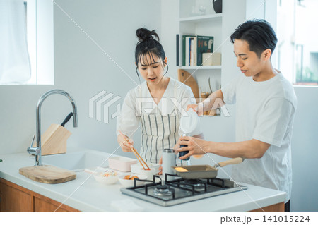ガスコンロを使いながらお弁当作りを分担するカップルのキッチンシーン ガスコンロを使いながらお弁当作りを分担するカップルのキッチンシーン 141015224