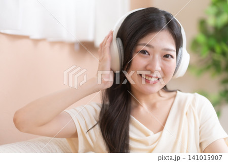 ワイヤレスヘッドフォンで音楽を楽しむ笑顔の若い女性 141015907