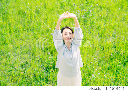 草原でストレッチをする若い女性 ライフスタイルイメージ 草原でストレッチをする若い女性 ライフスタイルイメージ 141016041