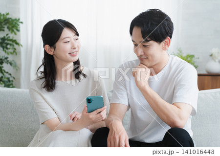 スマートフォンを操作する妊婦と夫　ライフスタイルイメージ 141016448