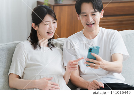 スマートフォンを操作する妊婦と夫　ライフスタイルイメージ 141016449