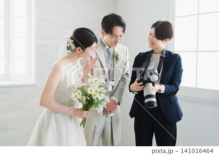 カメラマンが撮影した写真を確認する新婦と新郎 ウエディングイメージ カメラマンが撮影した写真を確認する新婦と新郎 ウエディングイメージ 141016464