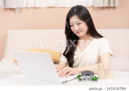ノートパソコンで住宅ローンやマイホーム購入を検討する若い女性 ノートパソコンで住宅ローンやマイホーム購入を検討する若い女性 141016766