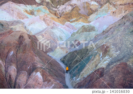 Inspiring aerial view of colorful canyon road in sierra nevada range. small yellow vehicle travels serene route through majestic pastel landscape of rocky terrain 141016830