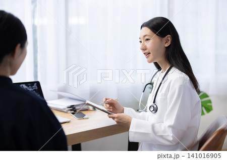 患者を診察する若い日本人の女性医師 患者を診察する若い日本人の女性医師 141016905