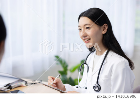 患者を診察する若い日本人の女性医師 患者を診察する若い日本人の女性医師 141016906
