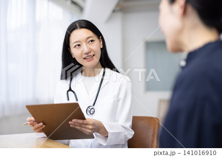 患者を診察する若い日本人の女性医師 患者を診察する若い日本人の女性医師 141016910