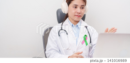 doctor using laptop for telehealth, online consultation and meeting about green and pink ribbon to patient for concept of October Metastatic Breast Cancer Awareness month, National Cancer Survivors doctor using laptop for telehealth, online consultation and meeting about green and pink ribbon to patient for concept of October Metastatic Breast Cancer Awareness month, National Cancer Survivors 141016989