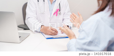 Doctor and patient having a medical consultation for Breast Cancer Awareness month, explaining a treatment plan, discussing diagnosis, and giving advice during a health checkup in hospital room 141017018