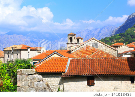 Old town with medieval houses and mountain, Herceg Novi, Montenegro. Topic of summer vacation, travel. Red-tiled rooftops in historic streets of Herceg Novi resting beneath towering mountain slopes 141018455