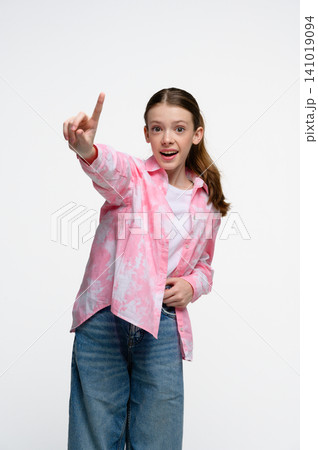 Surprised teenage girl pointing upward with raised finger and looking at camera. Surprised teenage girl pointing upward with raised finger and looking at camera. 141019094