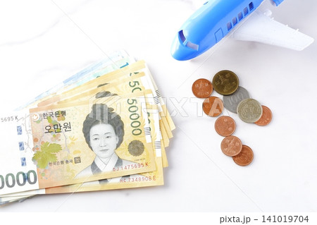 韓国の通貨、ウォンKRWの紙幣と飛行機で、韓国旅行に出発するイメージ 141019704