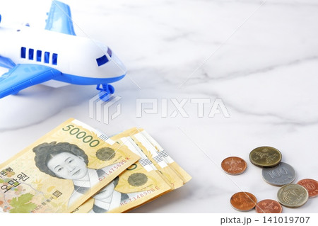 韓国の通貨、ウォンKRWの紙幣と飛行機で、韓国旅行に出発するイメージ 141019707