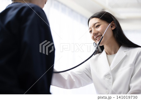 聴診器を使って診察する若い日本人の女性医師 聴診器を使って診察する若い日本人の女性医師 141019730