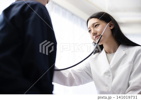 聴診器を使って診察する若い日本人の女性医師 聴診器を使って診察する若い日本人の女性医師 141019731