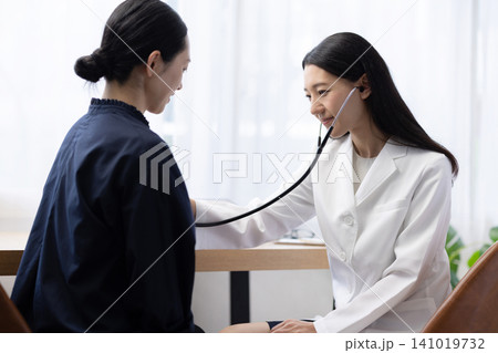 聴診器を使って診察する若い日本人の女性医師 聴診器を使って診察する若い日本人の女性医師 141019732