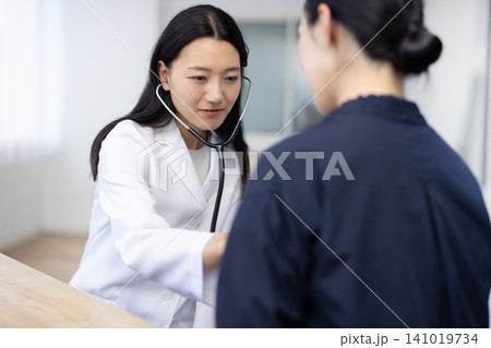 聴診器を使って診察する若い日本人の女性医師 聴診器を使って診察する若い日本人の女性医師 141019734