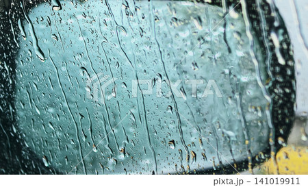 Heavy rain streaks flowing down car window with blurred vehicle outside 141019911