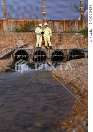 Industrial wastewater inspection team monitoring drainage system at factory site 141020483