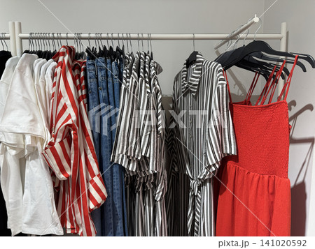 Red Summer Dress With Striped Clothing Displayed On Fashion Rack Together 141020592