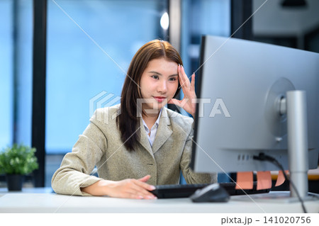 Focused Asian Businesswoman Working at Computer Desk in Modern Office with Confident Smile Focused Asian Businesswoman Working at Computer Desk in Modern Office with Confident Smile 141020756
