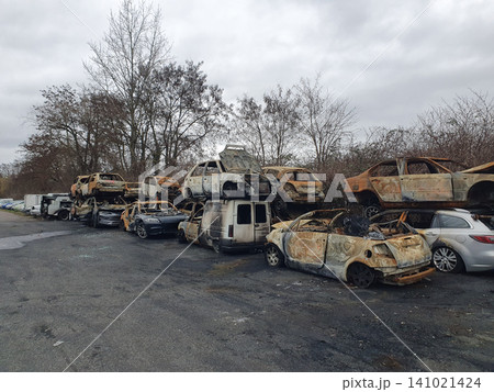 Stacked Burnt Cars And Abandoned Vehicles In Overgrown Scrapyard With Urban Decay Mood Stacked Burnt Cars And Abandoned Vehicles In Overgrown Scrapyard With Urban Decay Mood 141021424