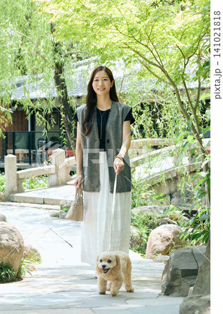 緑豊かな庭園で愛犬と散歩を楽しむ笑顔の若い女性 緑豊かな庭園で愛犬と散歩を楽しむ笑顔の若い女性 141021818