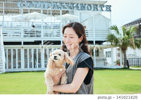 白いカフェの前で愛犬を抱く笑顔の若い女性 白いカフェの前で愛犬を抱く笑顔の若い女性 141021820