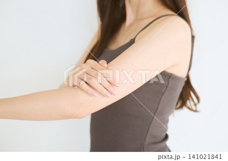 腕を押さえる女性 肘の痛みや肌荒れのイメージ 腕を押さえる女性 肘の痛みや肌荒れのイメージ 141021841