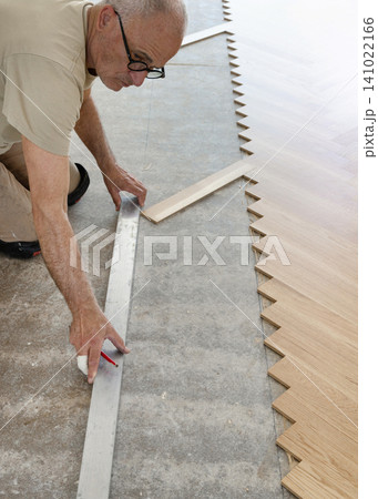 Carpenter measuring and marking layout for Italian herringbone parquet flooring installation Carpenter measuring and marking layout for Italian herringbone parquet flooring installation 141022166