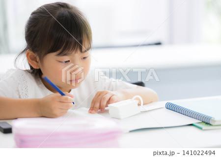 教室で計算ドリルに集中して取り組む幼稚園・小学生位の女の子・塾や学校、受験や勉強、学習のイメージ 141022494